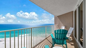 A balcony with a view of the ocean, a wooden floor, and two green chairs. - Dunes of Panama 2002e (Panama City Beach)