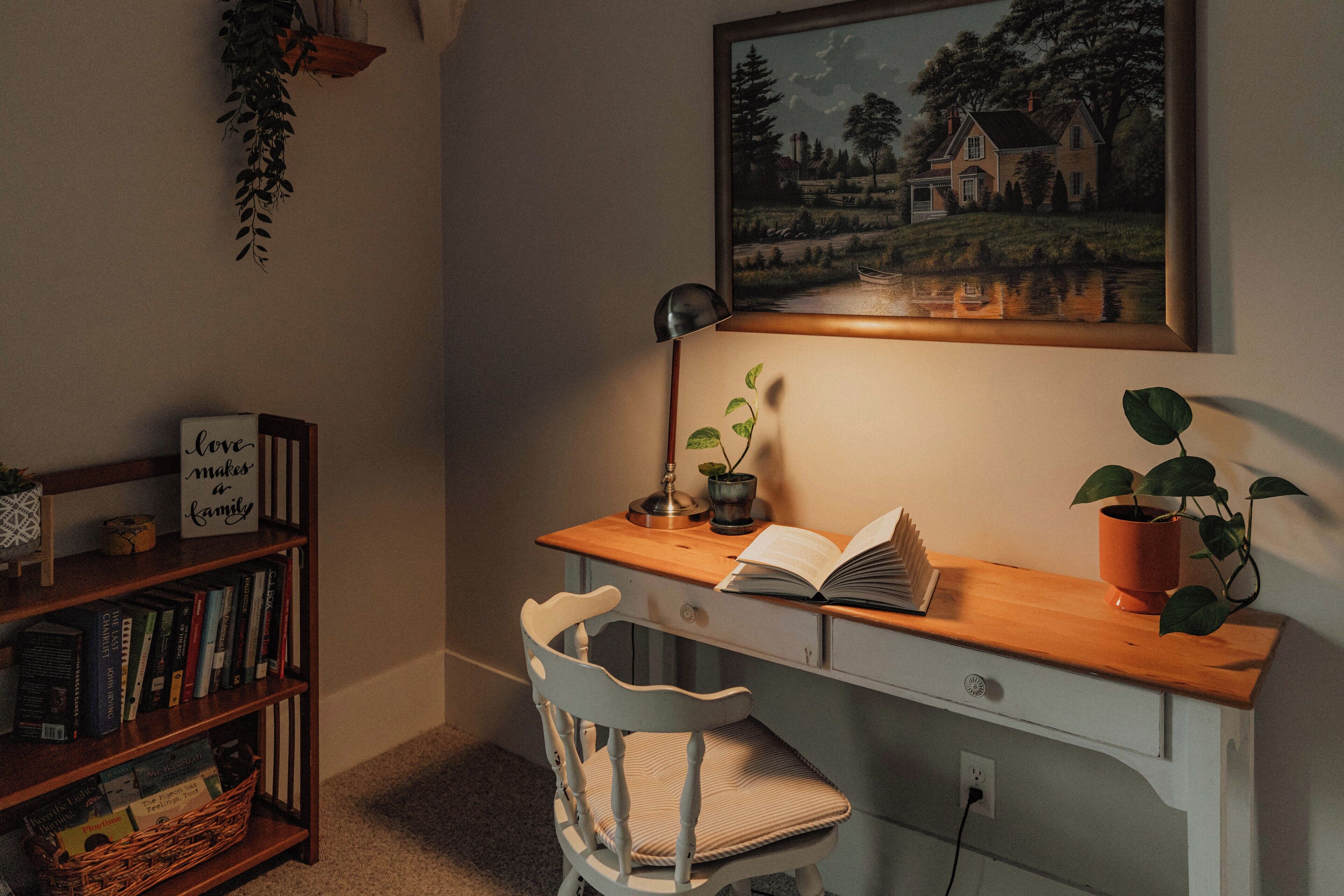A study area with a desk, chair, bookshelf, and a framed painting.