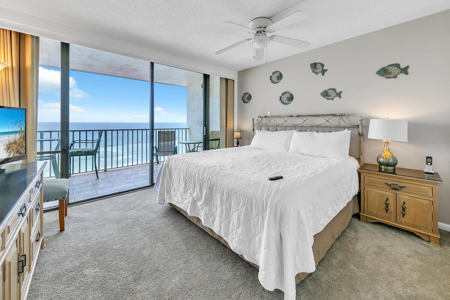 A bedroom with a large bed, a nightstand, a chair, and a view of the ocean.