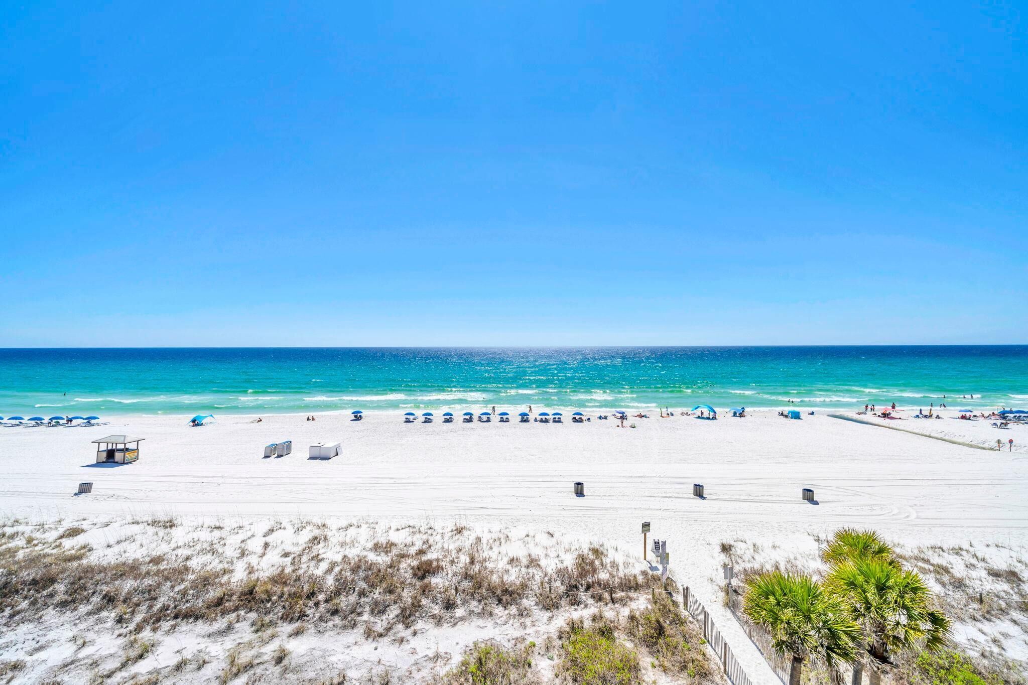 A beach with clear skies, a sandy shore, and a lifeguard tower.