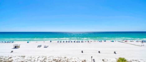 A beach with clear skies, a sandy shore, and a lifeguard tower.