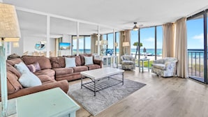 A spacious living room with a large sofa, a coffee table, and a view of the ocean.