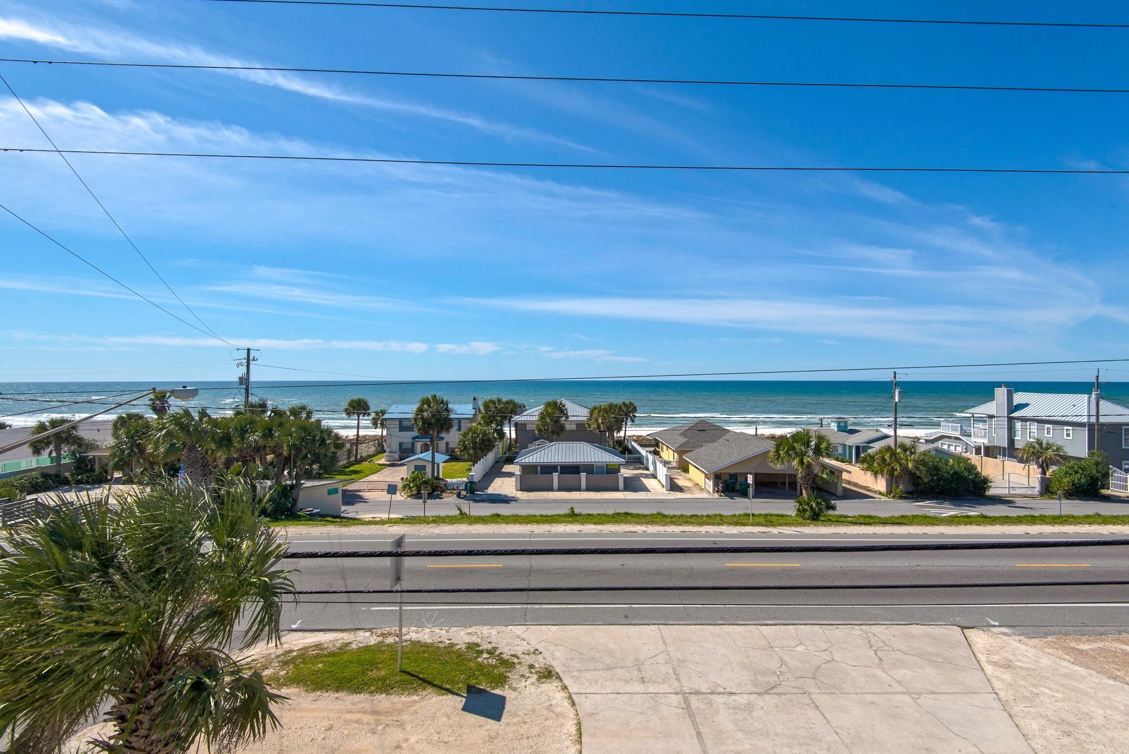 Ein Küstenwohngebiet mit Häusern, einer Straße und einem Strand im Hintergrund.