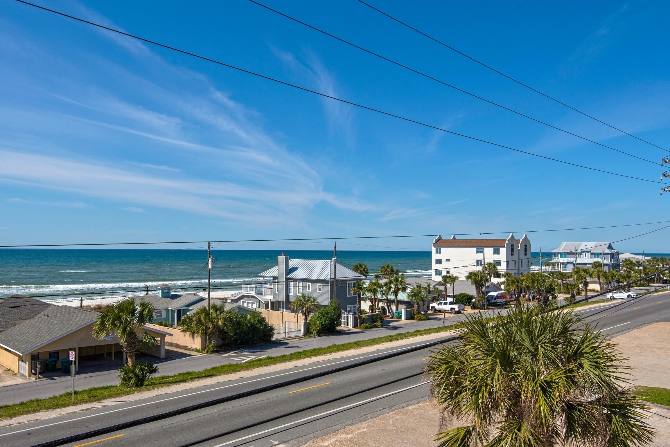 Une route côtière offrant une vue sur la plage, des maisons et un ciel dégagé.