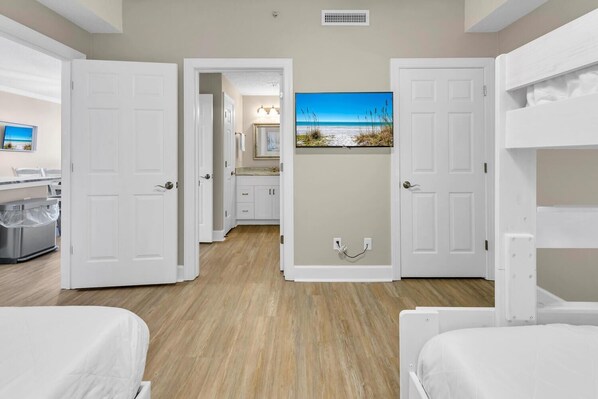 A hotel room with two beds, a bathroom, a kitchen area, and a hallway leading to another room. - Twin Palms 1401 (Panama City Beach)