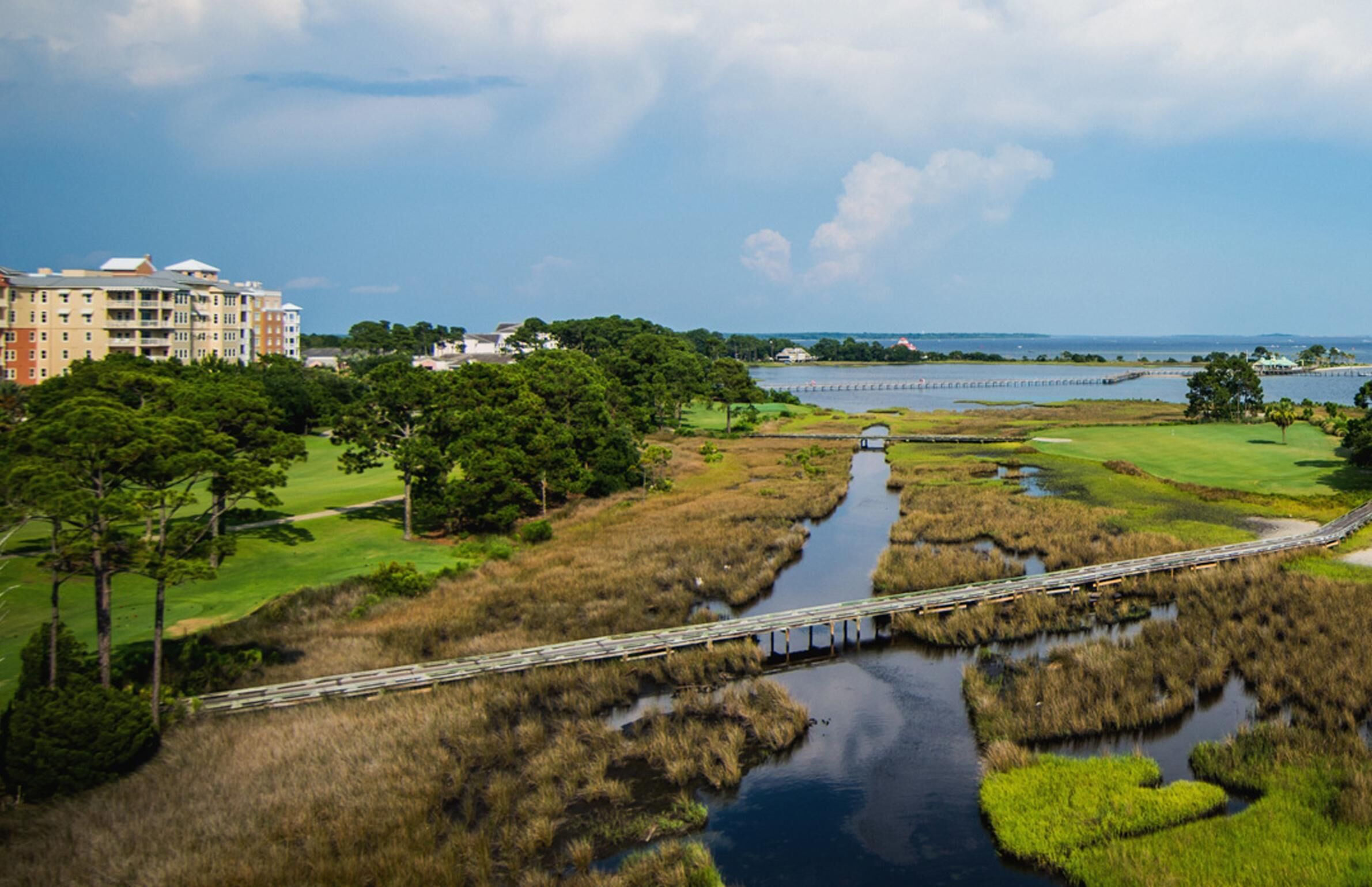 A coastal landscape with a bridge, grassy areas, and a body of water.