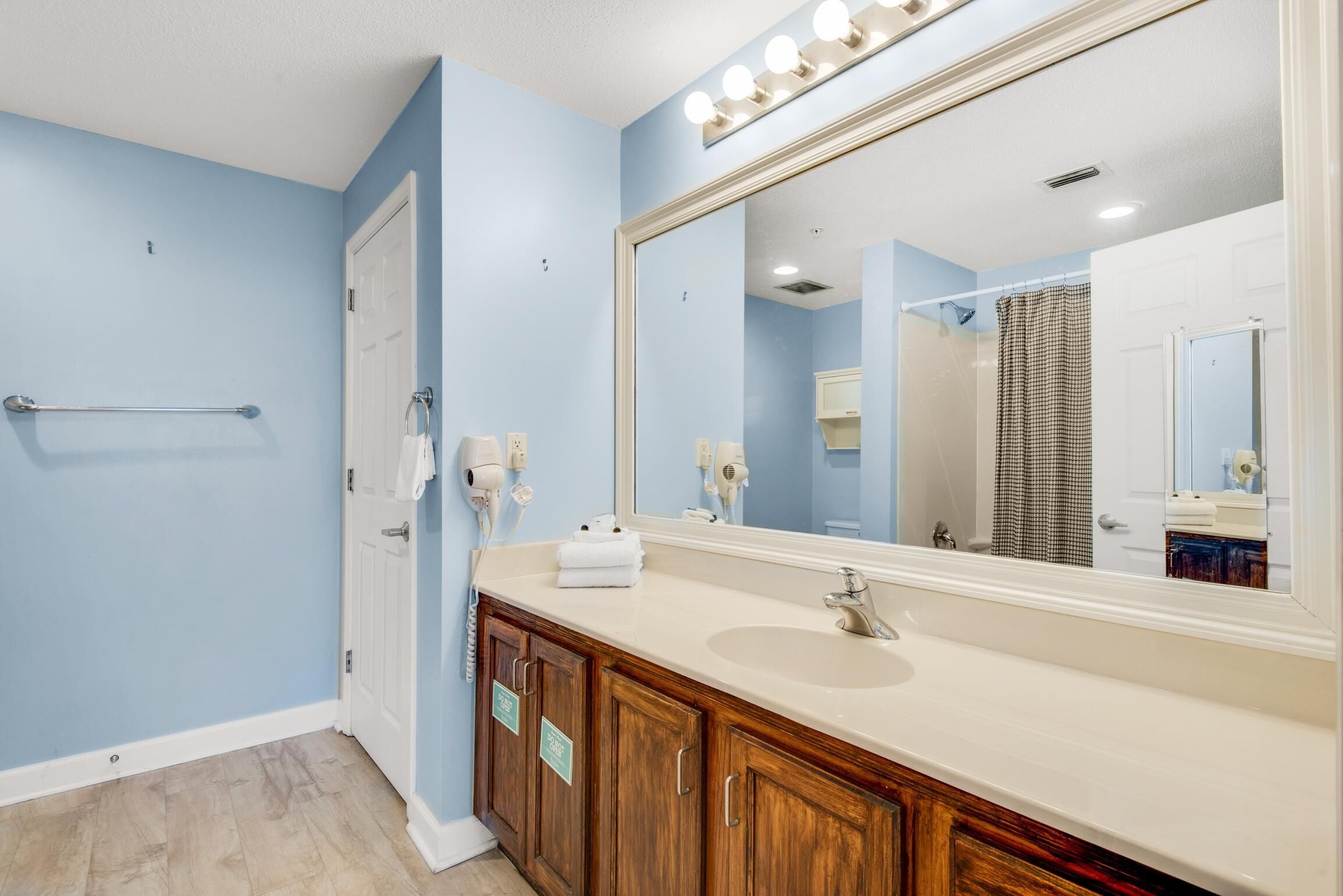 A bathroom with a large mirror, vanity, and a towel rack.