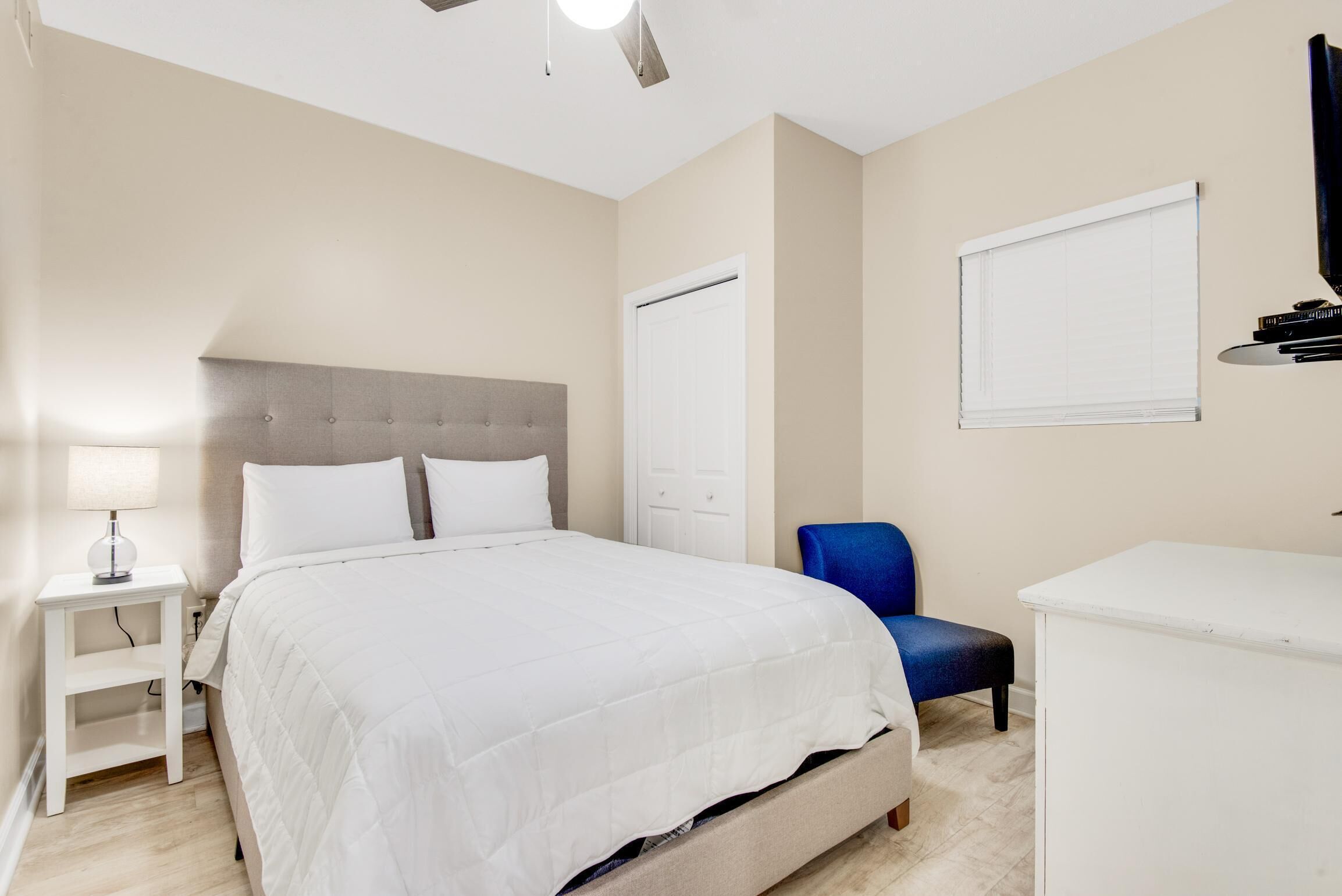 Une chambre à coucher comprenant un lit, une table de chevet, une chaise, un bureau et une armoire.