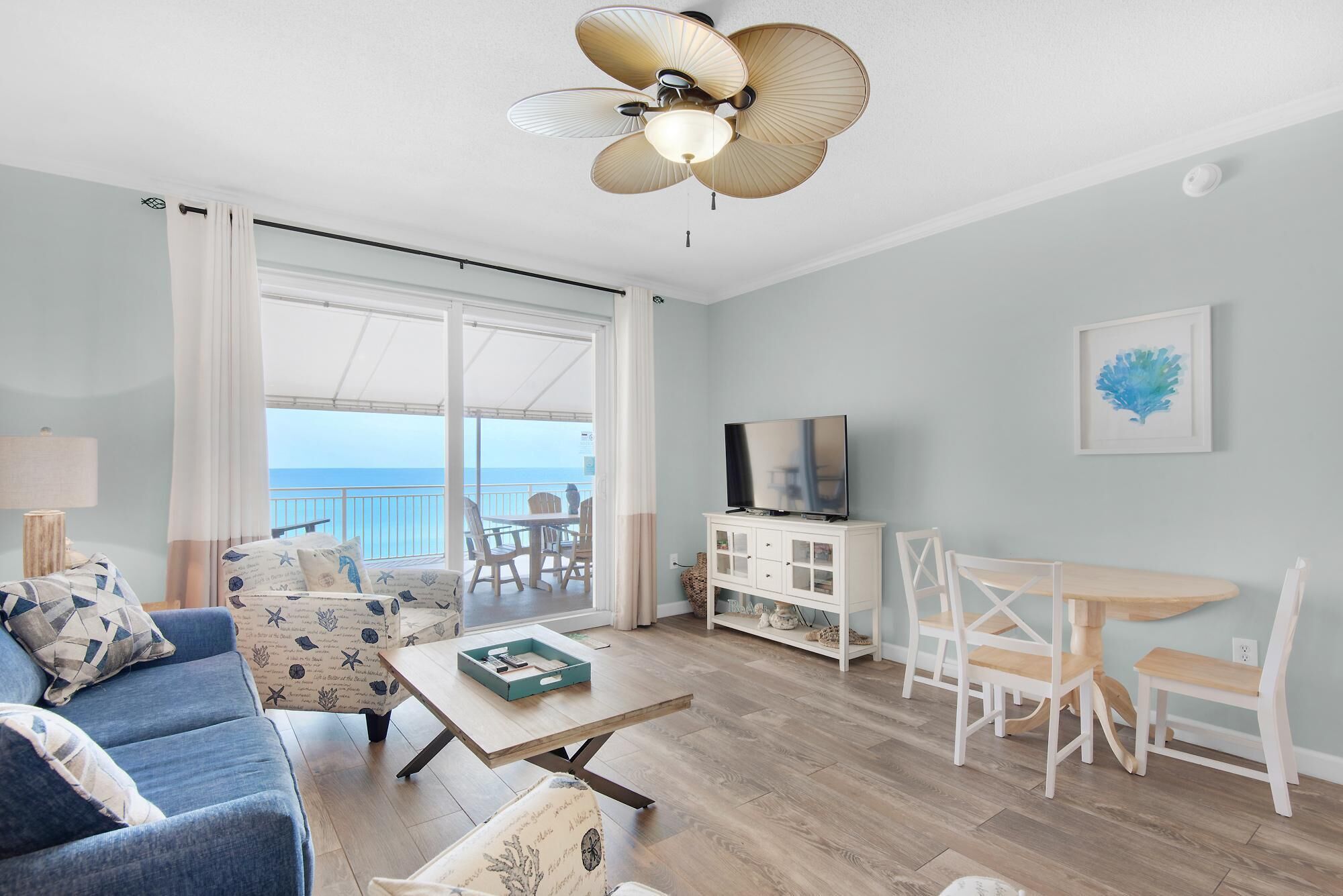 A living room with a sofa, coffee table, TV, and a balcony with a view.