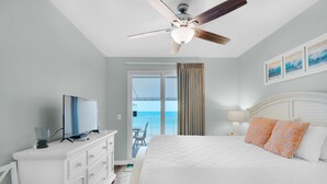 Una habitación de hotel con cama, televisión, cómoda y ventilador de techo.