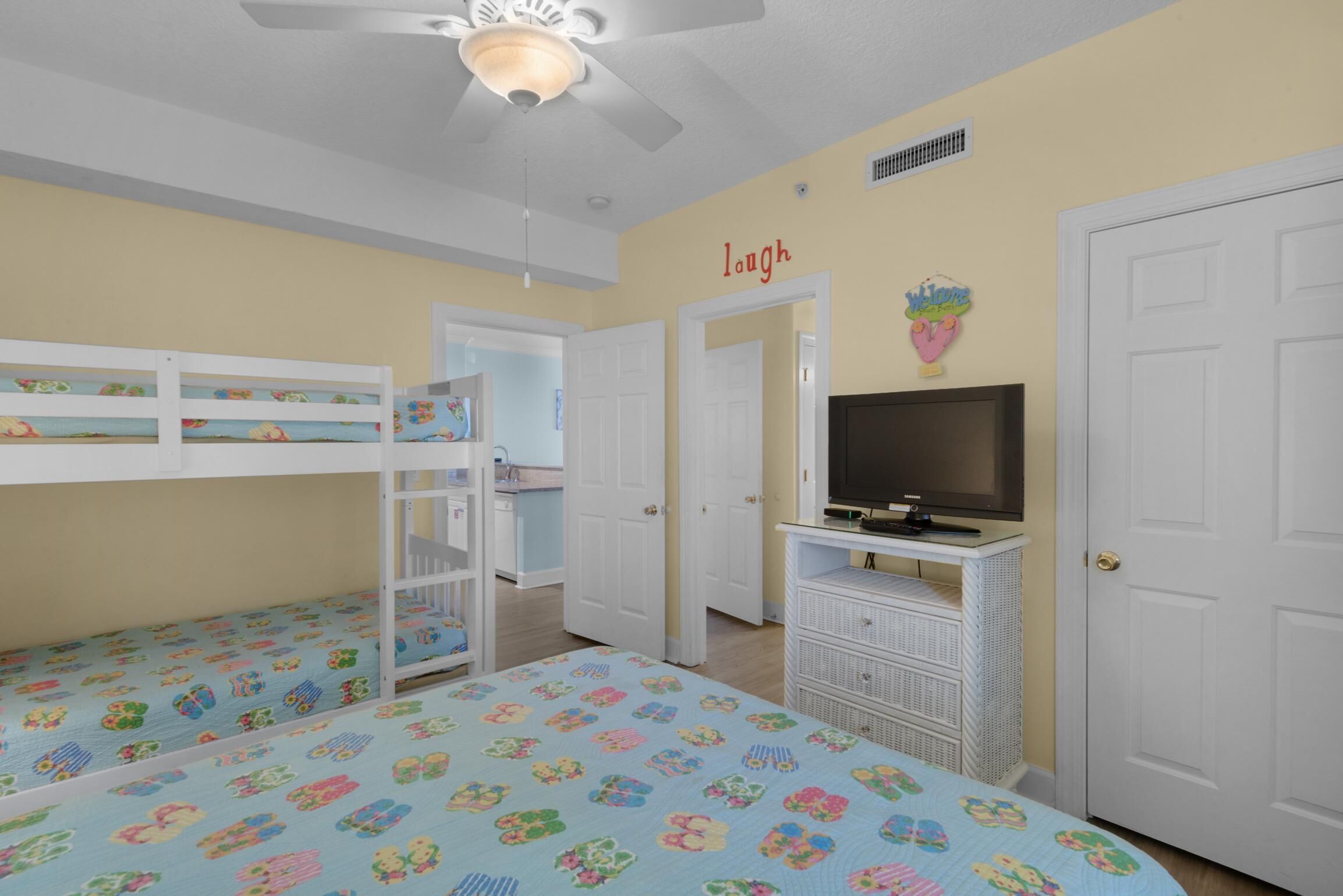 A child's bedroom with bunk beds, a television, and a door marked "lough".