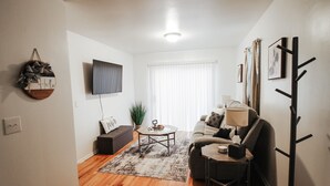 Un salon comprenant un canapé, une table basse et un téléviseur à écran plat fixé au mur.