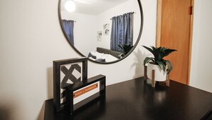 Une pièce avec un miroir rond, un tableau encadré, une petite plante en pot et une porte en bois.