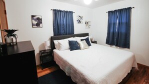 Une chambre à coucher avec un lit, des tables de chevet, un bureau et des rideaux.