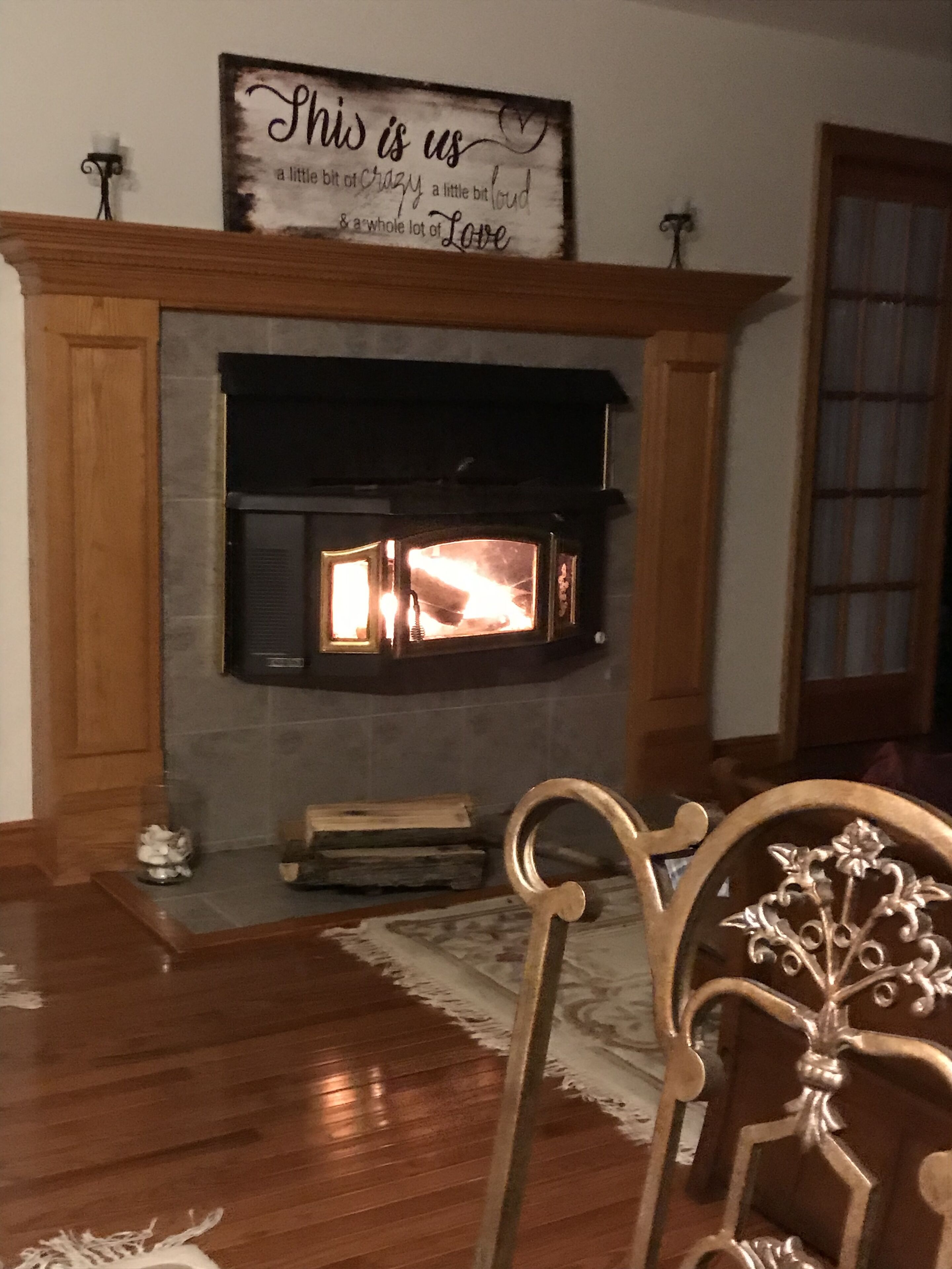 Un salon chaleureux avec une cheminée, un plancher en bois et un panneau décoratif au-dessus du manteau de cheminée.