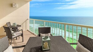 A balcony with wicker furniture, a table, and a view of the ocean. - Majestic Beach Towers 2-2003 (Panama City Beach)