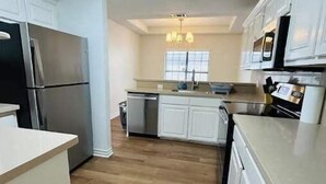 Een moderne keuken met witte kasten, roestvrijstalen apparatuur en een houten vloer.
