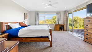 A bedroom with a bed, a desk, a dresser, and a ceiling fan. - RidgeRaj - Kerikeri Holiday Home (Kerikeri)