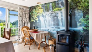 A dining area with a table, chairs, and a fireplace. - RidgeRaj - Kerikeri Holiday Home (Kerikeri)