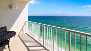 A balcony with a view of the ocean, a white railing, and a table with chairs. - Majestic Beach Towers 2-1803 (Panama City Beach)