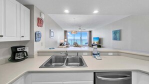 A modern kitchen with a double sink, white cabinets, and a view of the balcony. - Majestic Beach Towers 2-1803 (Panama City Beach)
