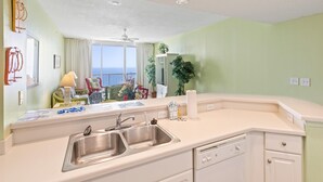 A kitchen with a double sink, dishwasher, and a view of the balcony. - Majestic Beach Towers 2-1803 (Panama City Beach)