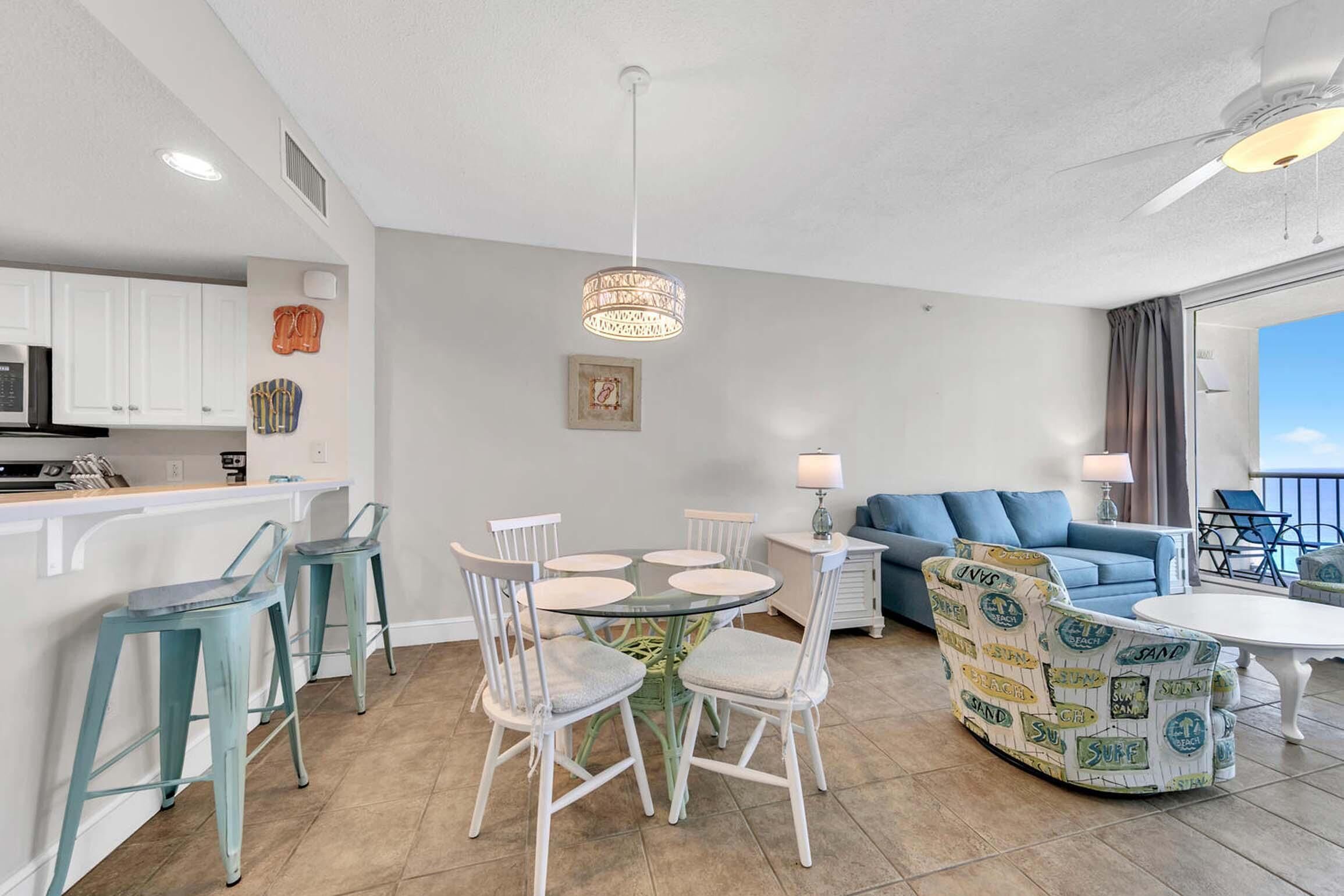 A modern living room with a round glass table, white chairs, a blue sofa, and a patterned armchair.