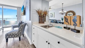 A modern kitchen with a large island, white cabinetry, and a view to the outside. - Majestic Beach Towers 2-1206 (Panama City Beach)