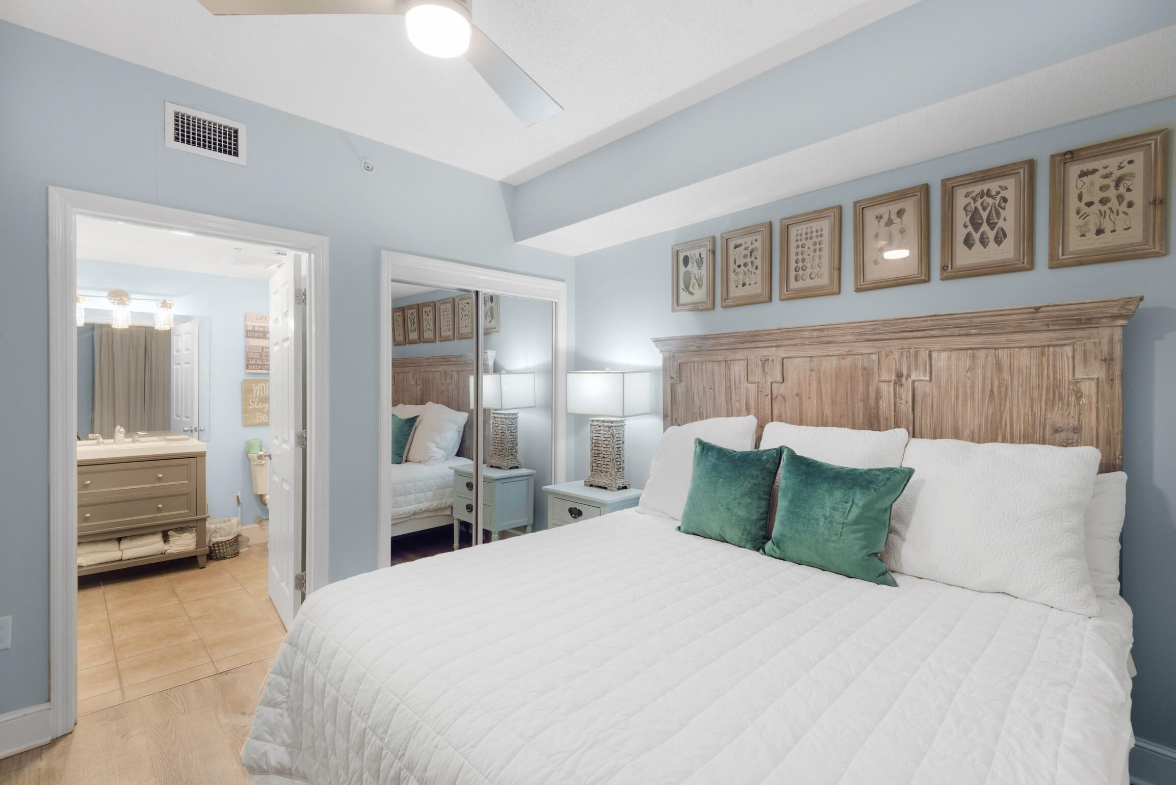 A bedroom with a large bed, a wooden headboard, bedside tables, and a mirror.