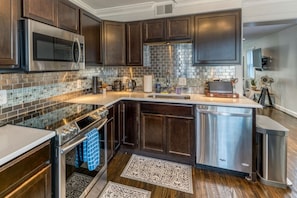 A modern kitchen with dark wood cabinets, stainless steel appliances, and a tiled backsplash.