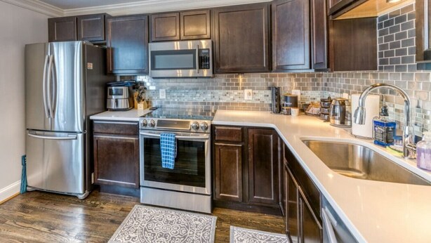 A modern kitchen with stainless steel appliances, dark wood cabinetry, and a tiled backsplash. - Quiet DC Retreat | 3BR | Sleeps 8 (Washington)