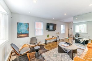 A modern living room with a sofa, chairs, a coffee table, and artwork on the walls.