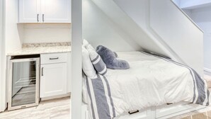A bedroom with a bed, pillows, a window, and a built-in desk with cabinets. - Quiet DC Retreat | 3BR | Sleeps 8 (Washington)