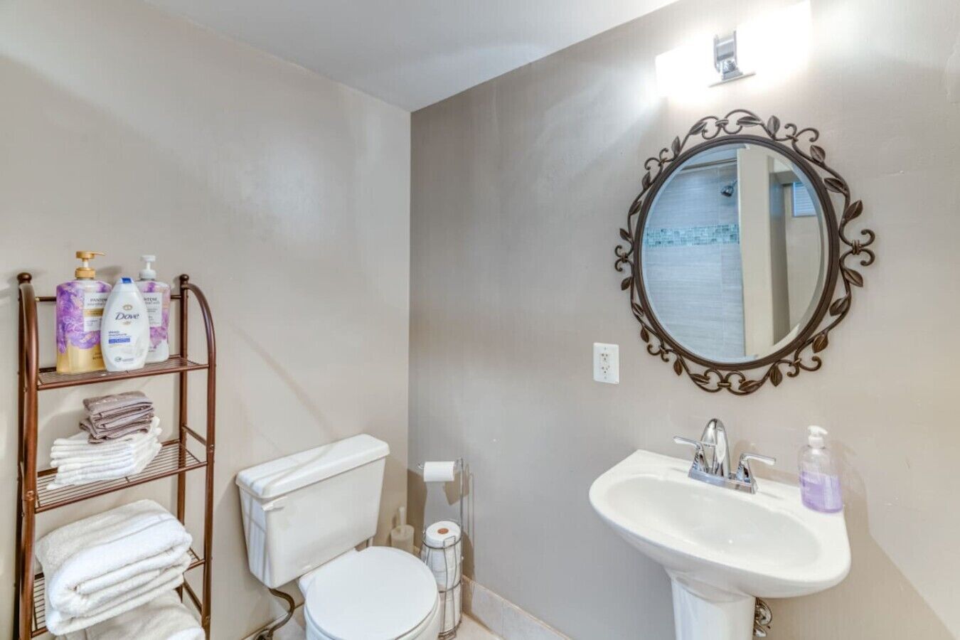 Un bagno con il water, un lavandino, uno specchio e uno scaffale con articoli da toilette.