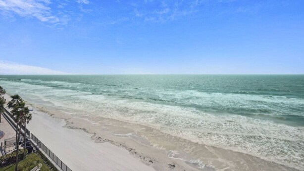 A beach view with a clear sky and ocean waves.