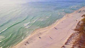 A beach with a pier extending into the water, sandy beach, and people enjoying the area. - Majestic Beach Towers 1-1706 (Panama City Beach)