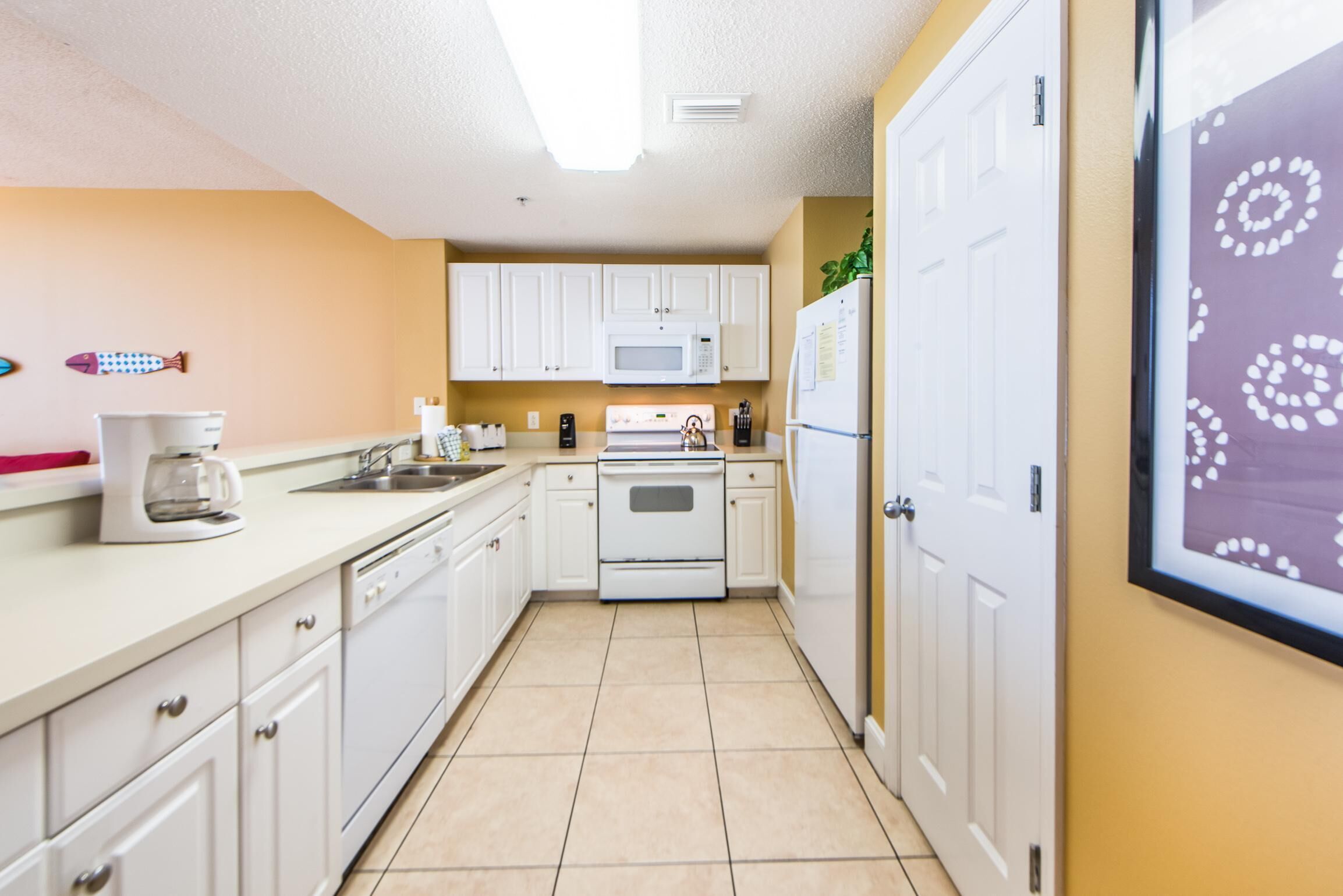 A compact kitchen with white cabinets, a microwave, a stove, and a refrigerator.