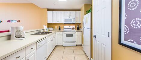 A compact kitchen with white cabinets, a microwave, a stove, and a refrigerator.