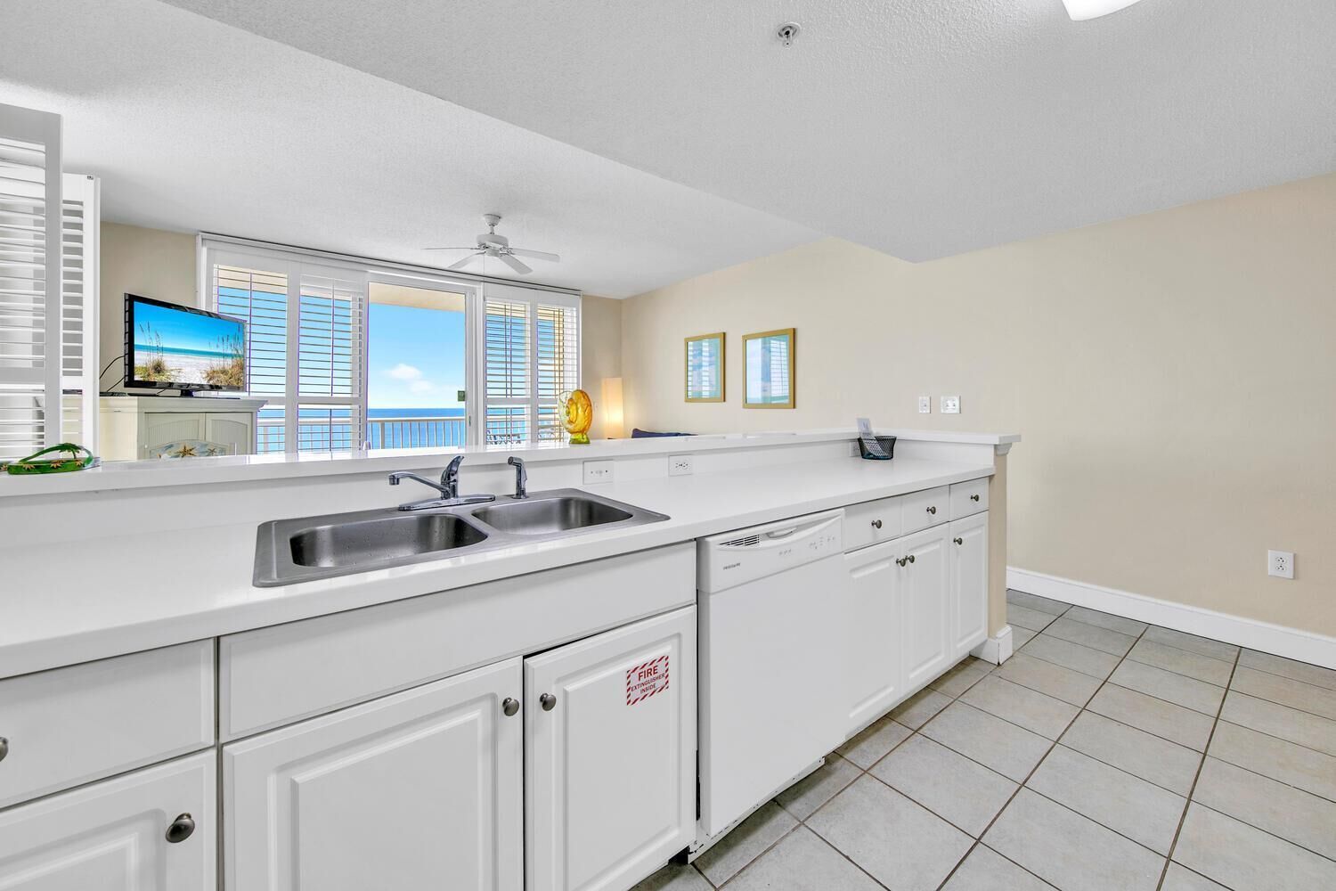 A kitchen with white cabinets, a double sink, and a ceiling fan.