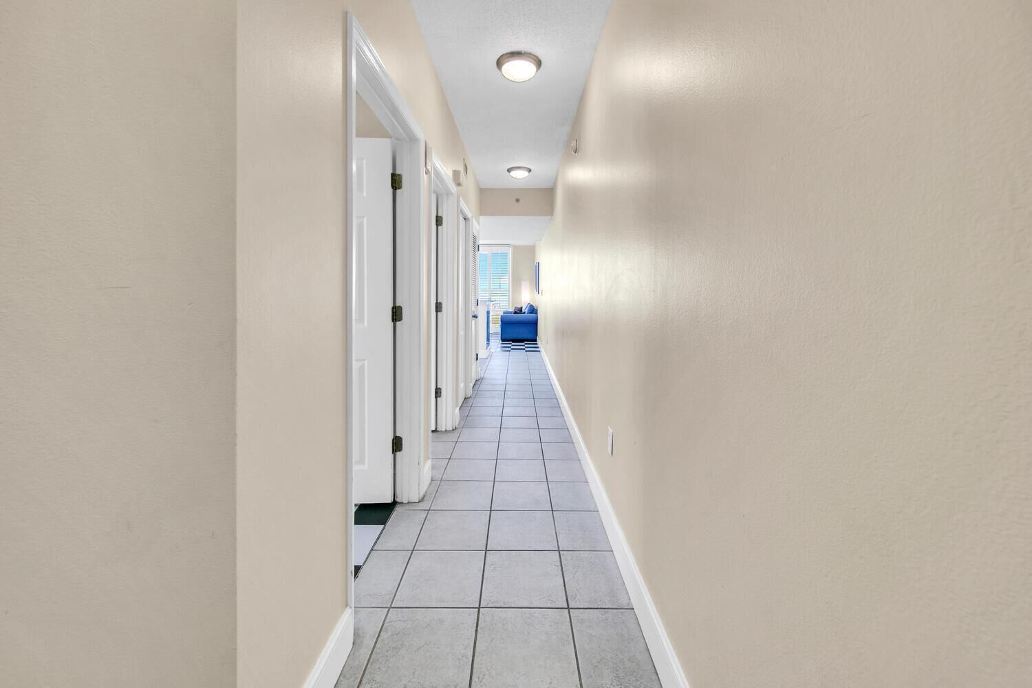 A narrow hallway with white doors and a tiled floor.