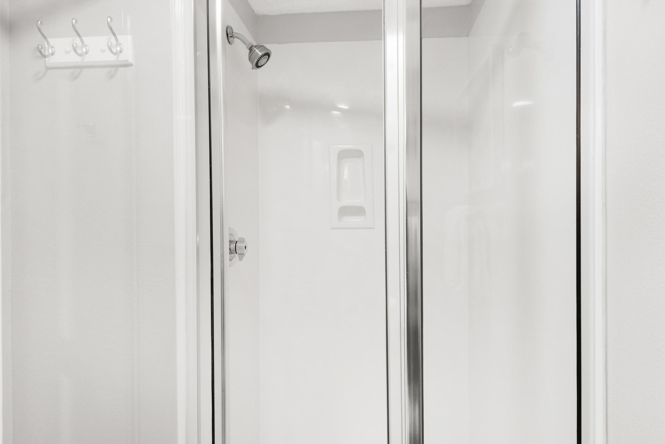 A modern bathroom with a glass shower enclosure, a white sink, and a towel rack.