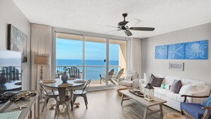 A spacious living room with a balcony overlooking the ocean, a ceiling fan, and a dining area with a view. - Majestic Beach Towers 1-1006 (Panama City Beach)