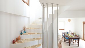A staircase with stone steps and a glass railing leading to a dining area with a wooden table and chairs. - Angelika House -Amazing Sea view (Faistos)