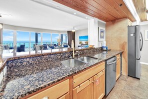 A kitchen with granite countertops, stainless steel appliances, and wooden cabinets. - Long Beach Resort 2-201 (Panama City Beach)
