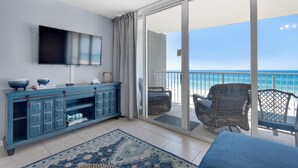 Un balcon avec vue sur l’océan, un canapé bleu, un téléviseur et un meuble bleu.