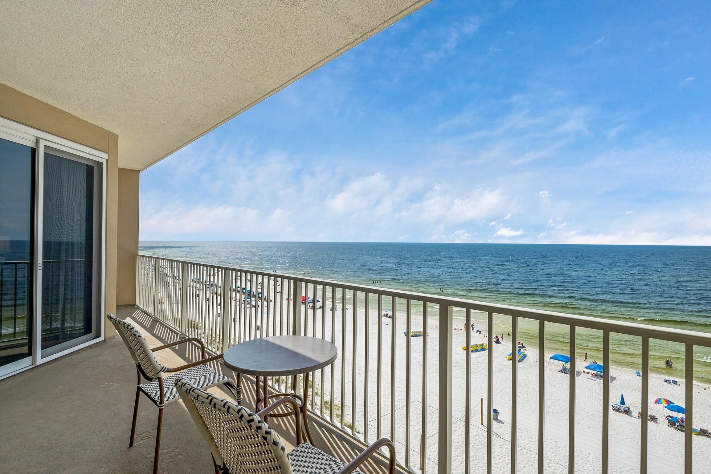 A balcony with a view of the beach, featuring a table and chairs.