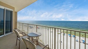 A balcony with a view of the beach, featuring a table and chairs.