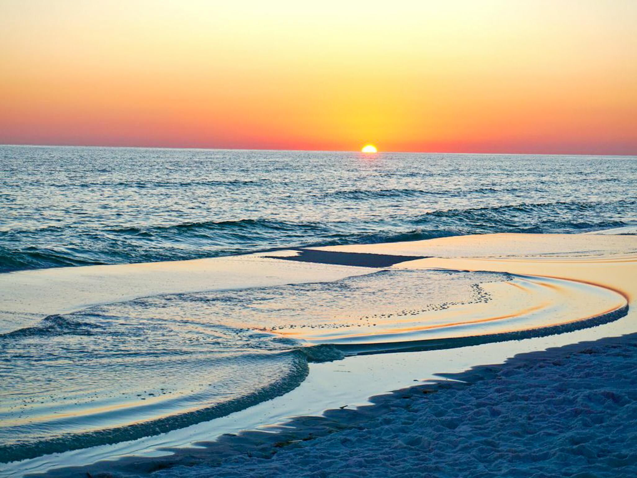 A beach with a sunset over the ocean.