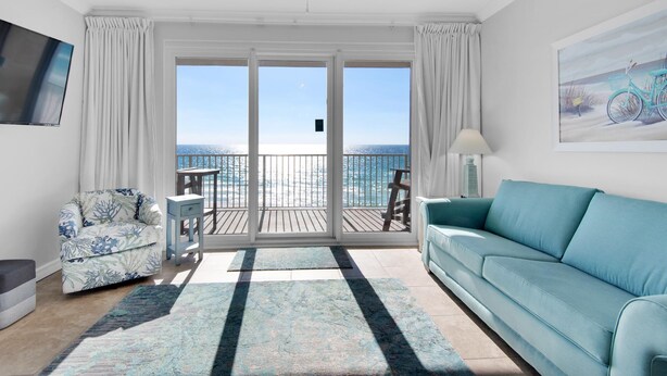 A spacious living room with a large sliding glass door leading to a balcony with a view of the ocean. - Grandview East 304 (Panama City Beach)