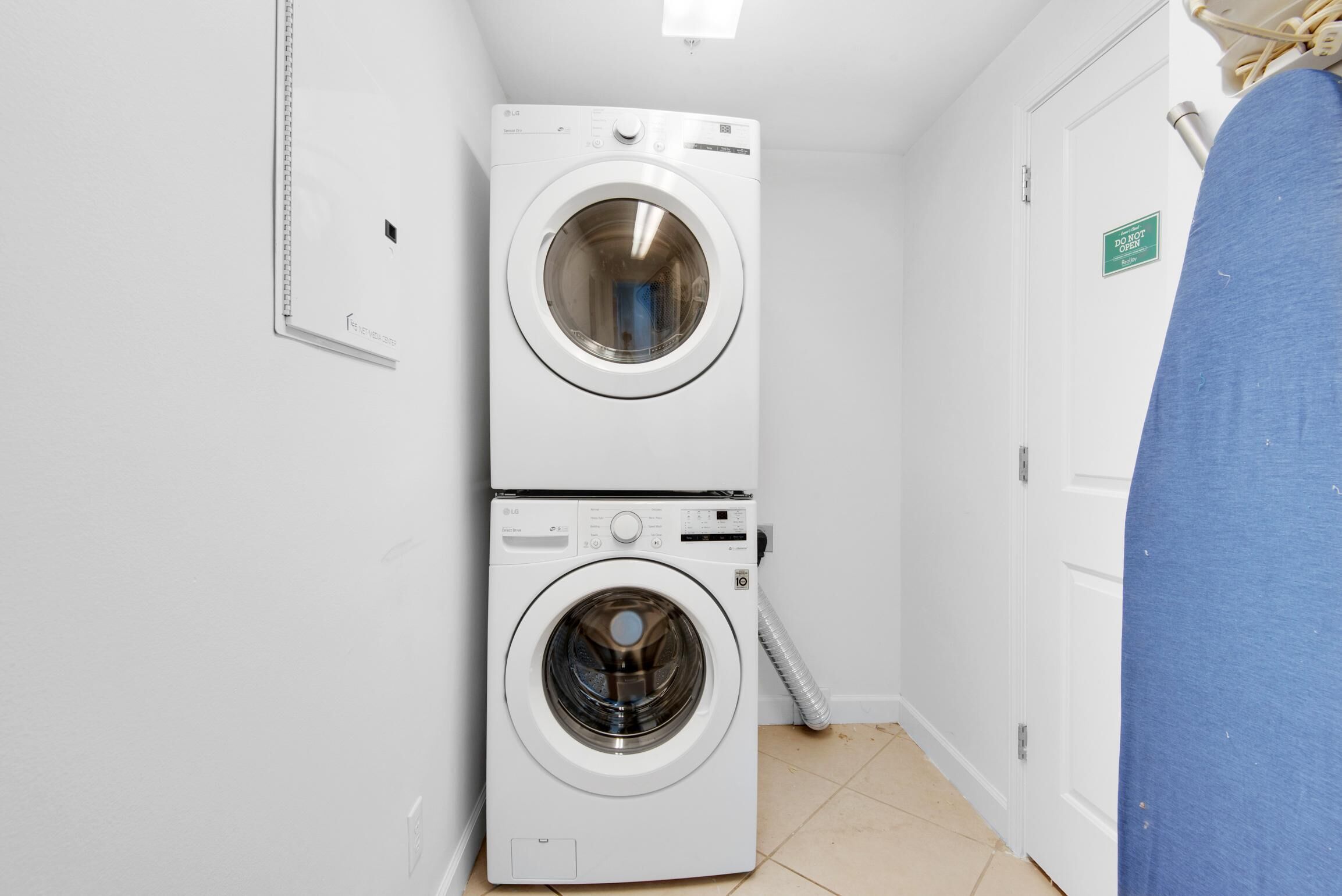 Ein Waschraum mit zwei übereinander gestapelten Waschmaschinen und einem blauen Vorhang.